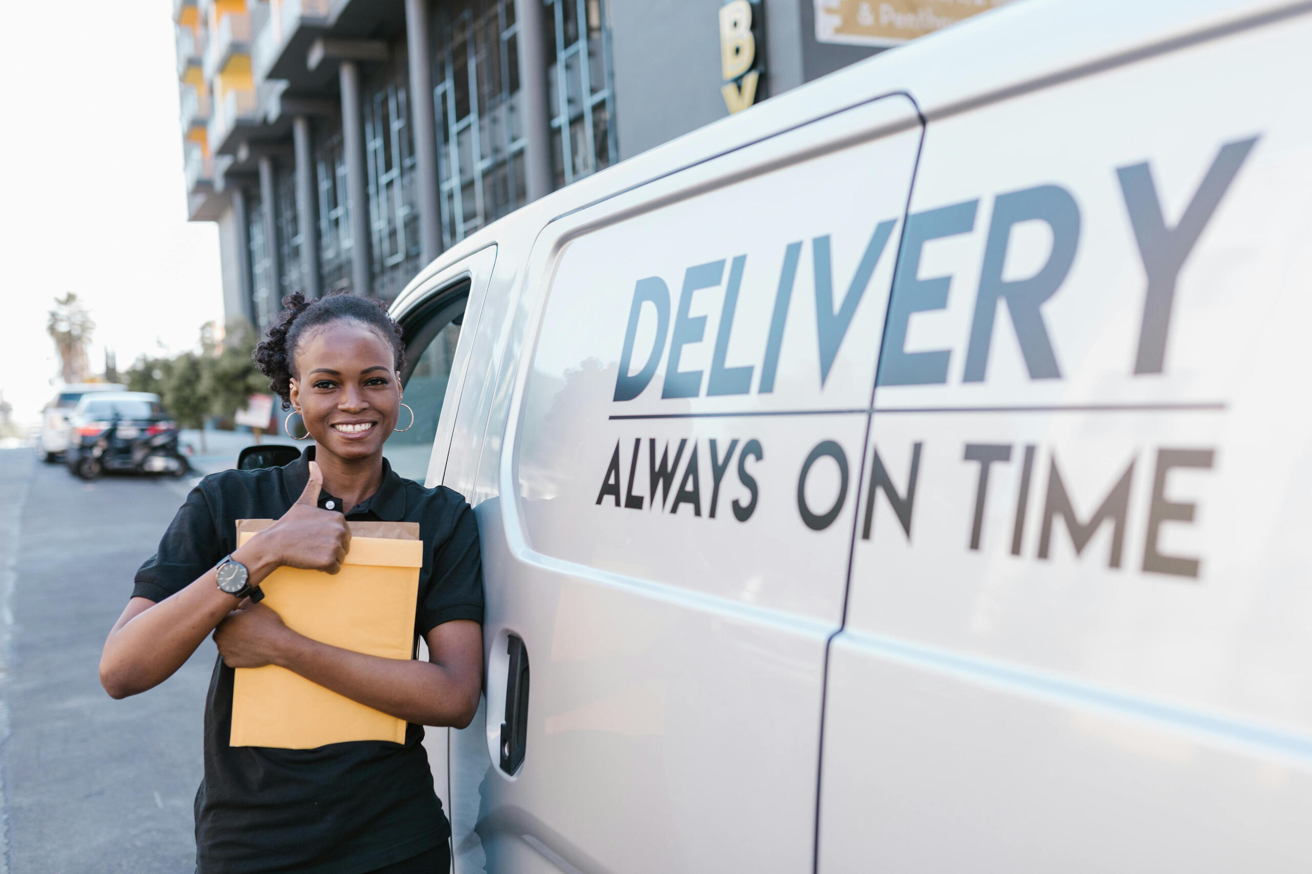 female courier standing outside of van